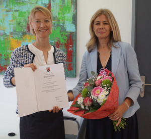 Vizepräsidentin am Sozialgericht Speyer Dr. Ulrike Pletscher (r.) bekommt von der Präsidentin des Sozialgerichts Speyer Dr. Britta Wiegand (l.) die Dankesurkunde überreicht